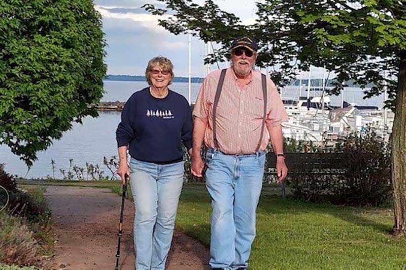 A happy elderly couple walks along the waterfront in Bayfield, Wisconsin