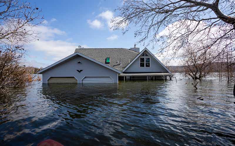 Following extreme flooding, only the top half of a two-story house is visible