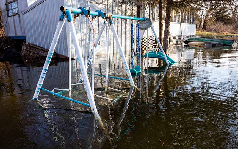 A swing set is submerged in a flooded yard