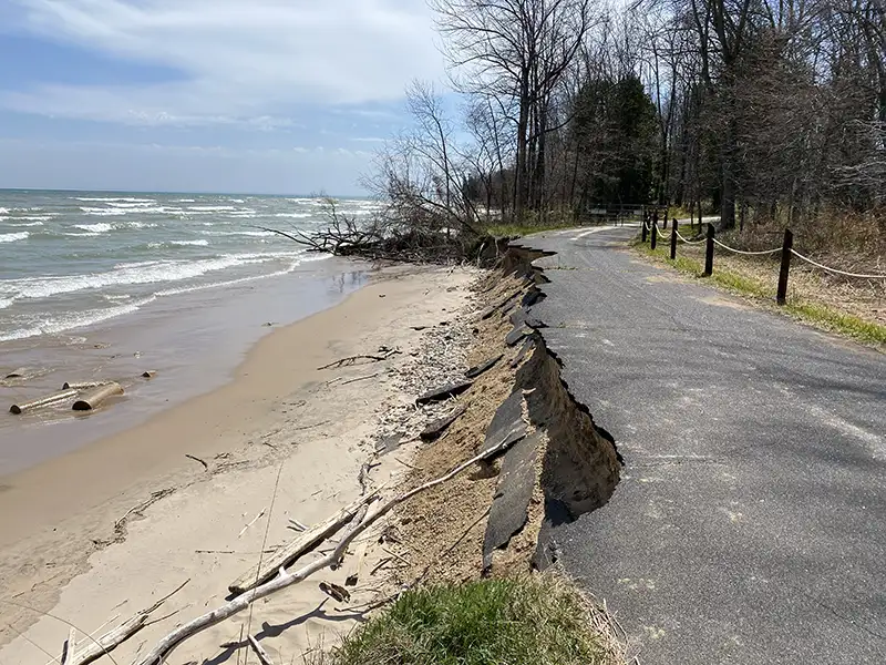 A beach-side road collapsing onto the beach due to erosion.