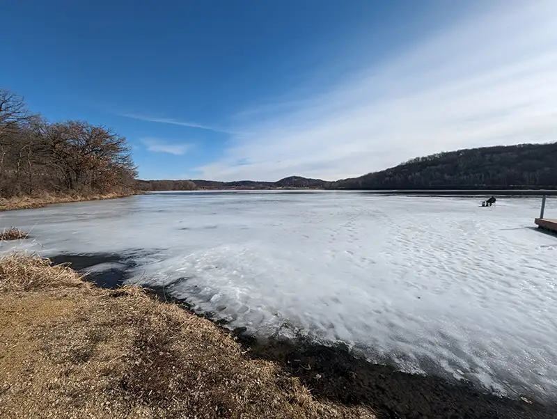 Ice fishing on a small lake with signs of melting ice.